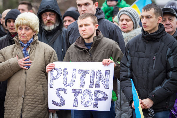 Protesto na Ucrânia contra a invasão da Crimeia em 2014, com um rapaz segurando um cartaz pedindo para que Putin pare. [3]