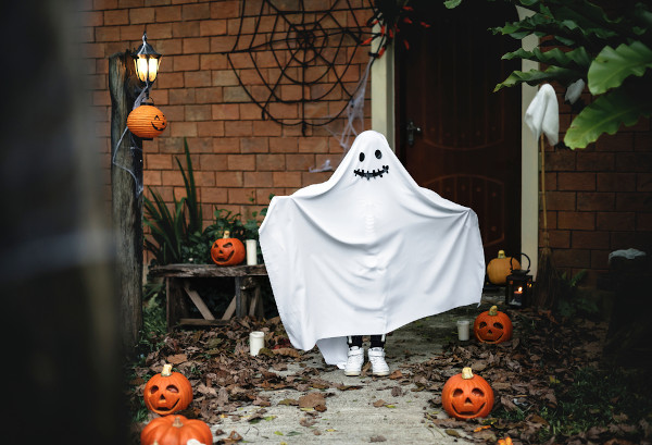 Pessoa fantasiada da fantasma em um ambiente decorado com abóboras de Halloween.