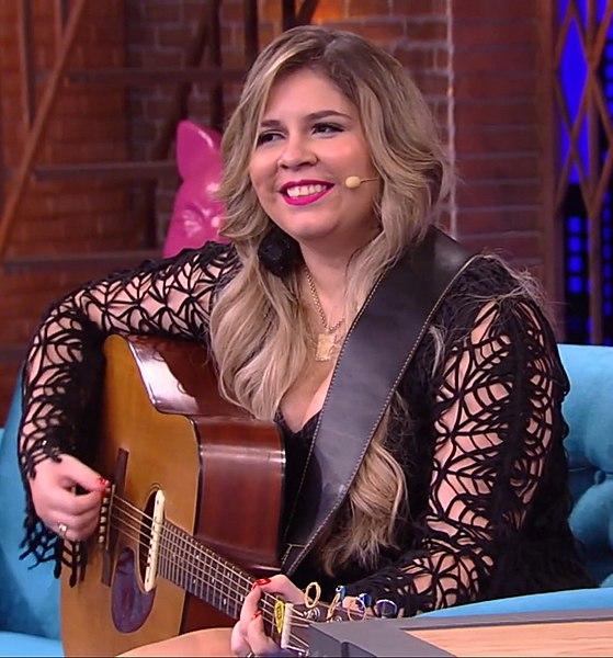 Marília Mendonça cantando e tocando violão