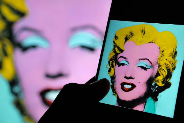 Foto de Marilyn Monroe retratada por Andy Warhol vista por um celular.