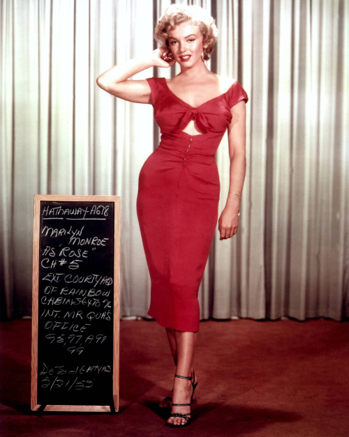 Marilyn Monroe de corpo inteiro, usando um vestido vermelho, no filme “Torrentes da paixão”.