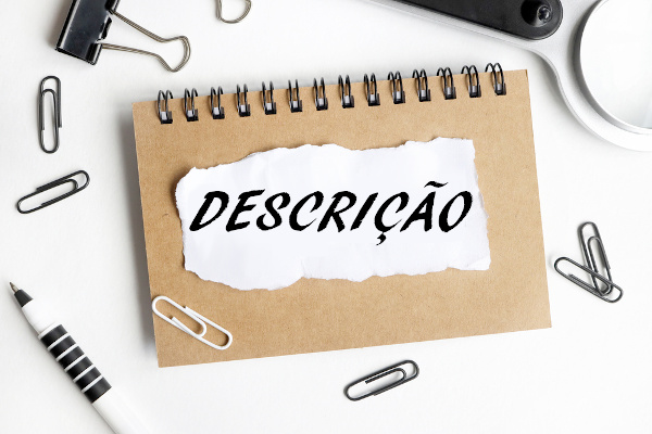 Palavra “Descrição” escrita sobre papel recortado que está em cima de caderneta.