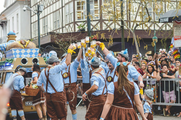 Participantes da Oktoberfest brindam com canecas de cerveja.