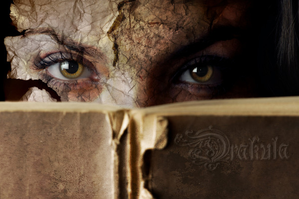 Rosto de uma mulher coberto pelo livro “Drácula” para representar a ideia de literatura fantástica.