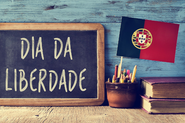 Quadro com o escrito “dia da liberdade” próximo à bandeira de Portugal, representando a relevância da Revolução dos Cravos.