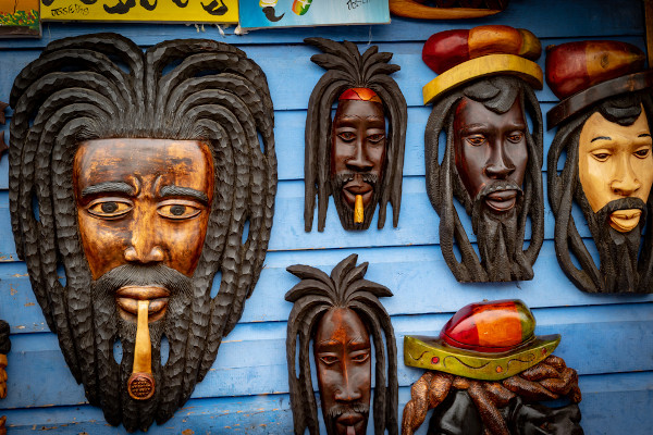 Esculturas de madeira de rostos de homens negros com dreadlocks no cabelo, típicos da cultura rastafári e do reggae.