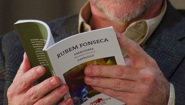 Vista aproximada das mãos de uma pessoa segurando o livro Amalgama de Rubem Fonseca.