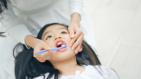 Dentista fazendo escovação com flúor em criança.