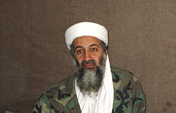 Osama bin Laden com uma barba longa e grisalha, vestido com roupa militar e turbante na cabeça.