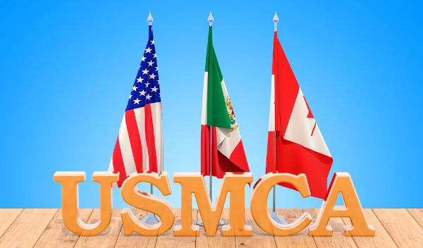 Bandeiras dos países do USMCA, o novo Nafta, hasteadas atrás do escrito “USMCA”.