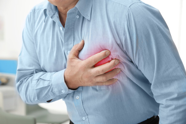 Homem com a mão no peito com sintoma de insuficiência cardíaca.