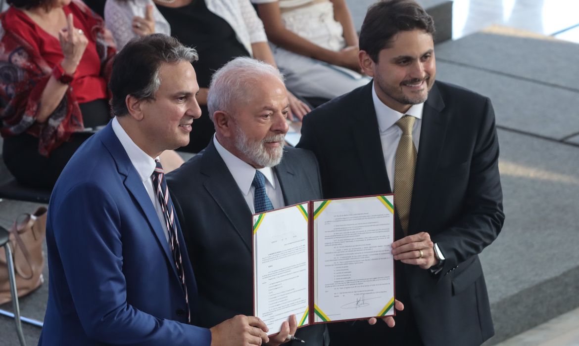 minstro da educação e minsitros das comunicação abraçam o presidente Lula e seguram um documento