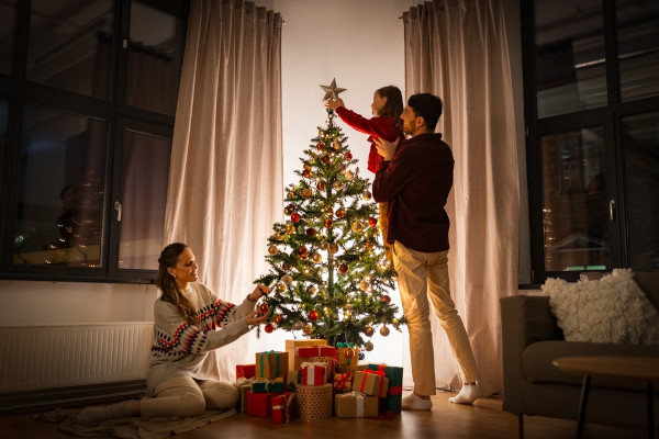 Família decorando uma Árvore de Natal, prática que surgiu na Europa do século XV, curiosidade sobre o Natal.