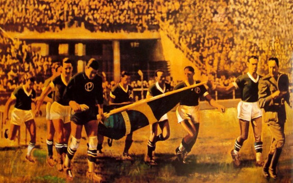 Jogadores do Palmeiras entram em estádio segurando uma bandeira do Brasil e acompanhados de um oficial do exército em 1942.