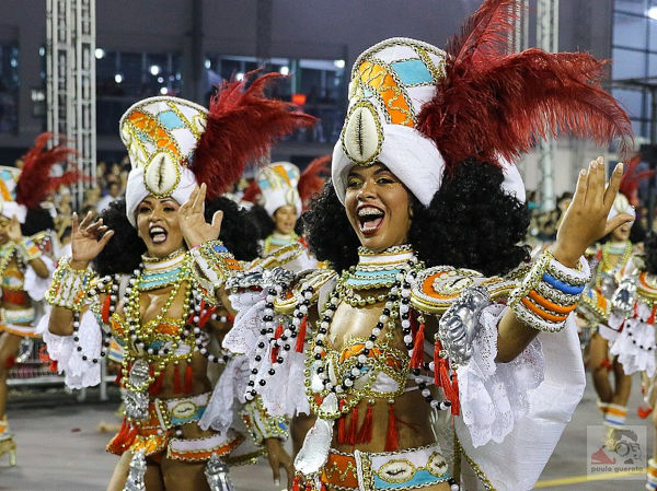 Mulheres sorridentes desfilando em uma escola de samba, em texto sobre harmonia e evolução.