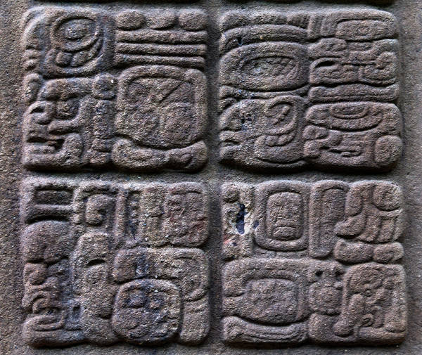 Exemplo de glifos maias esculpidos em uma estela na Guatemala, parte importante da história da escrita.