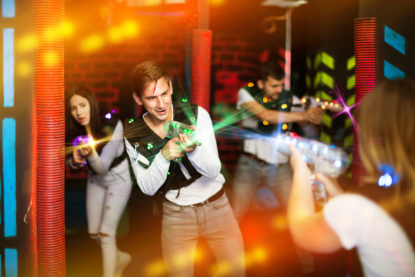 Pessoas se divertindo em momento de lazer com armas a laser em uma arena de laser tag.