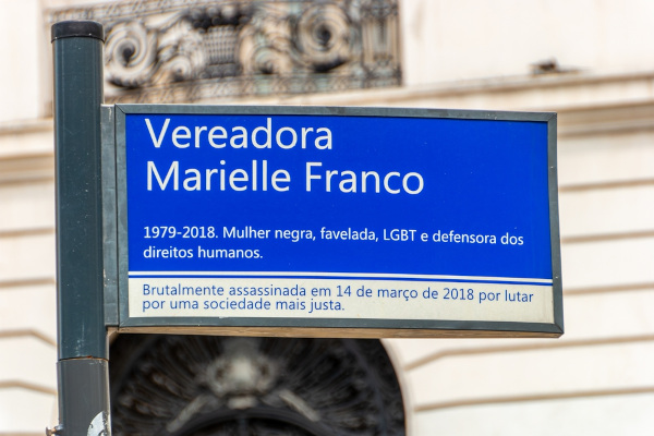 Placa na rua que homenageia a vereadora Marielle Franco, em texto sobre milícia.