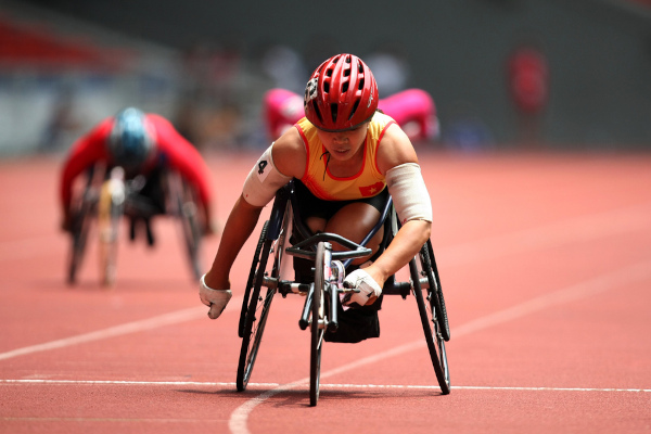 Atleta em cadeira de roda na pista de atletismo durante prova do paratletismo.  