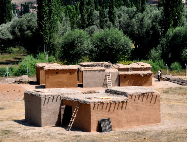 Reconstrução de habitações de uma aldeia neolítica em texto sobre sedentarização.