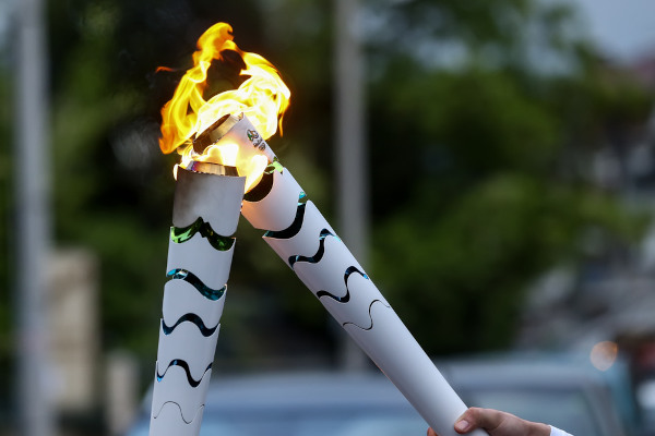 Foto de uma tocha olímpica acendendo a outra.