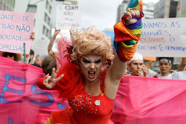 Drag queen protesta em frente a cartazes contra a homofobia em uma passeata, no Brasil.