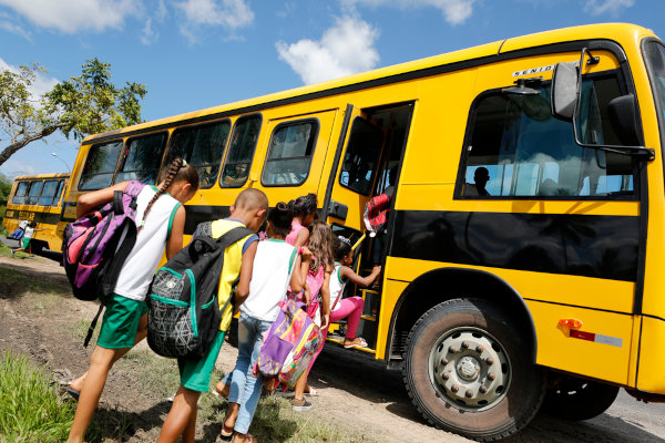 Crianças entrando em ônibus escolar, em texto sobre educação no Brasil.