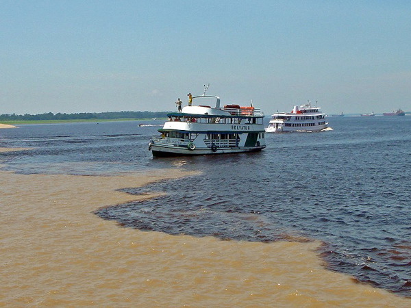 Embarcação navegando no encontro das águas do rio Solimões com o rio Negro.