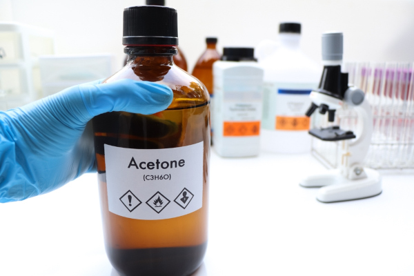 Químico manuseando em laboratório um vidro com acetona, o tipo mais comum das cetonas.