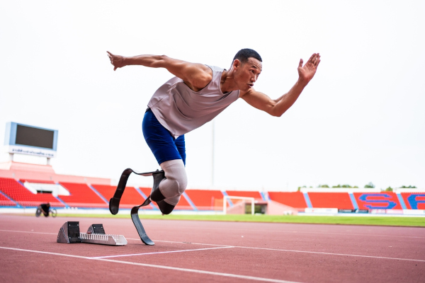 Corredor com próteses em estádio praticando atletismo, um dos esportes paralímpicos.