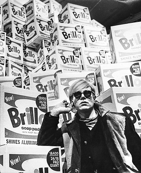 Andy Warhol, artista do movimento pop art, em frente a uma de suas obras.