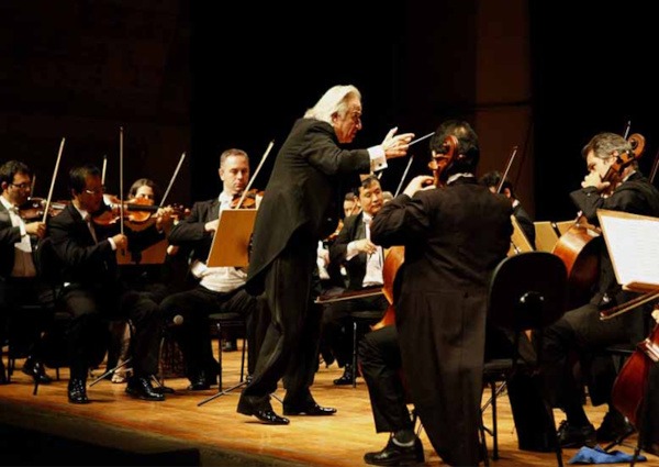 João Carlos Martins como maestro, regendo uma orquestra.