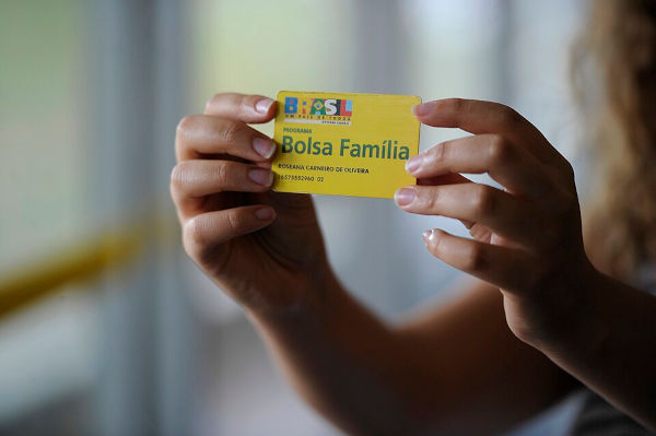 Mãos segurando um cartão do Bolsa Família, programa que faz parte das políticas públicas do Brasil.