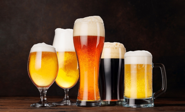 Copos, canecas e taças de vidro com diferentes tipos de cerveja, uma bebida alcoólica.