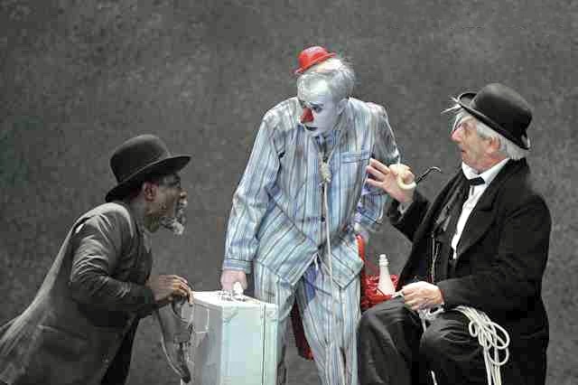Dois homens conversando com um palhaço em cena de “Esperando Godot”, obra que faz parte da história do teatro moderno.