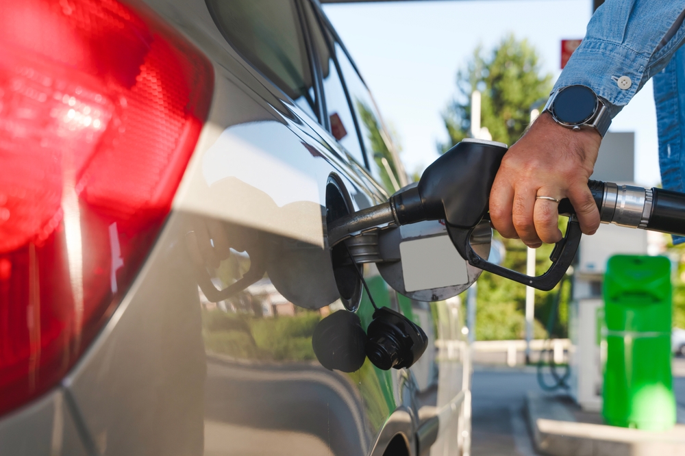 Mão abastecendo carro com gasolina, um exemplo de composto químico orgânico.