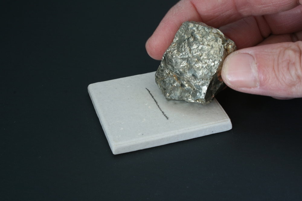 Teste de traço de um mineral em placa de porcelana.