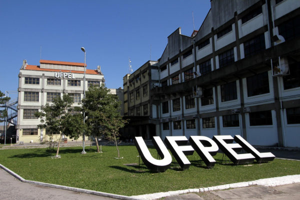 Fundo azul. Foto do campus da UFPel. Texto Vestibular 2023 Vagas Remanescentes via Enem