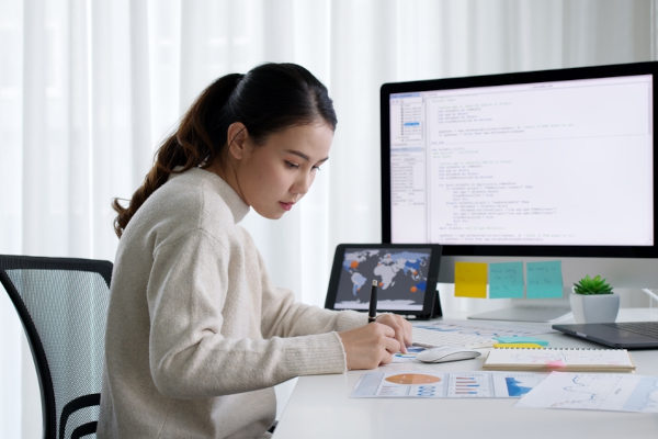 Estudante em mesa com telas de computares e tablet